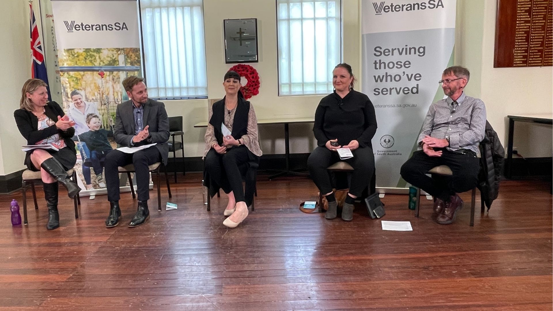 Five participants seated in front of pull up banners at a Veterans SA Community Conversation event