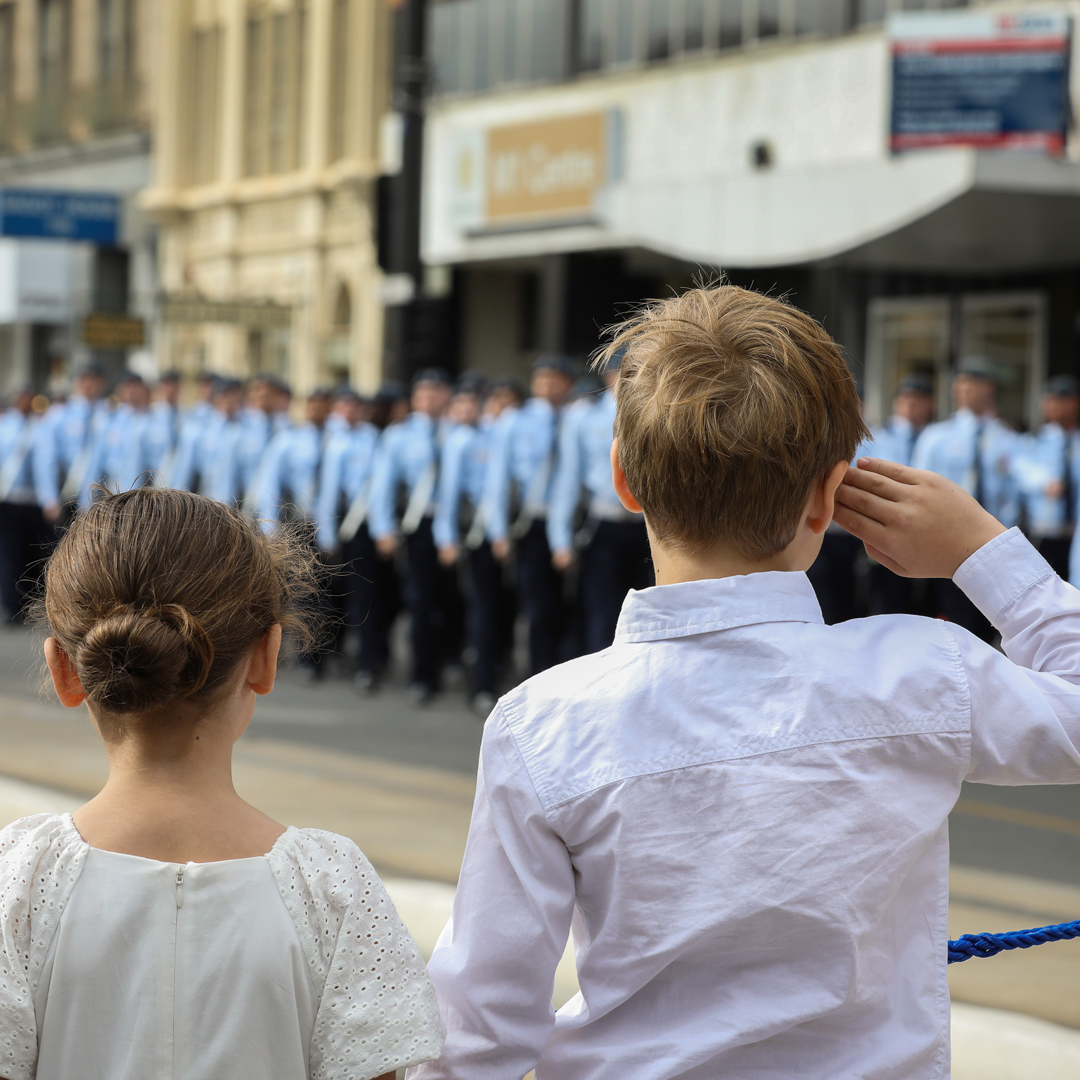 Two small children watching Royal Australian Air Force members march on Anzac Day