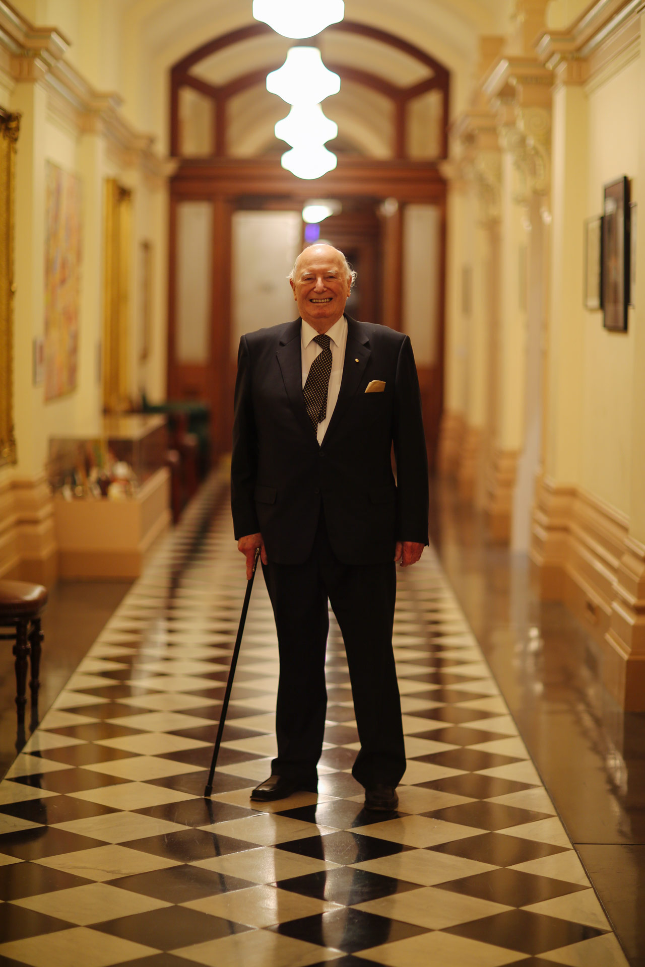 Sir Eric Neal standing in a hallway smiling at the camera