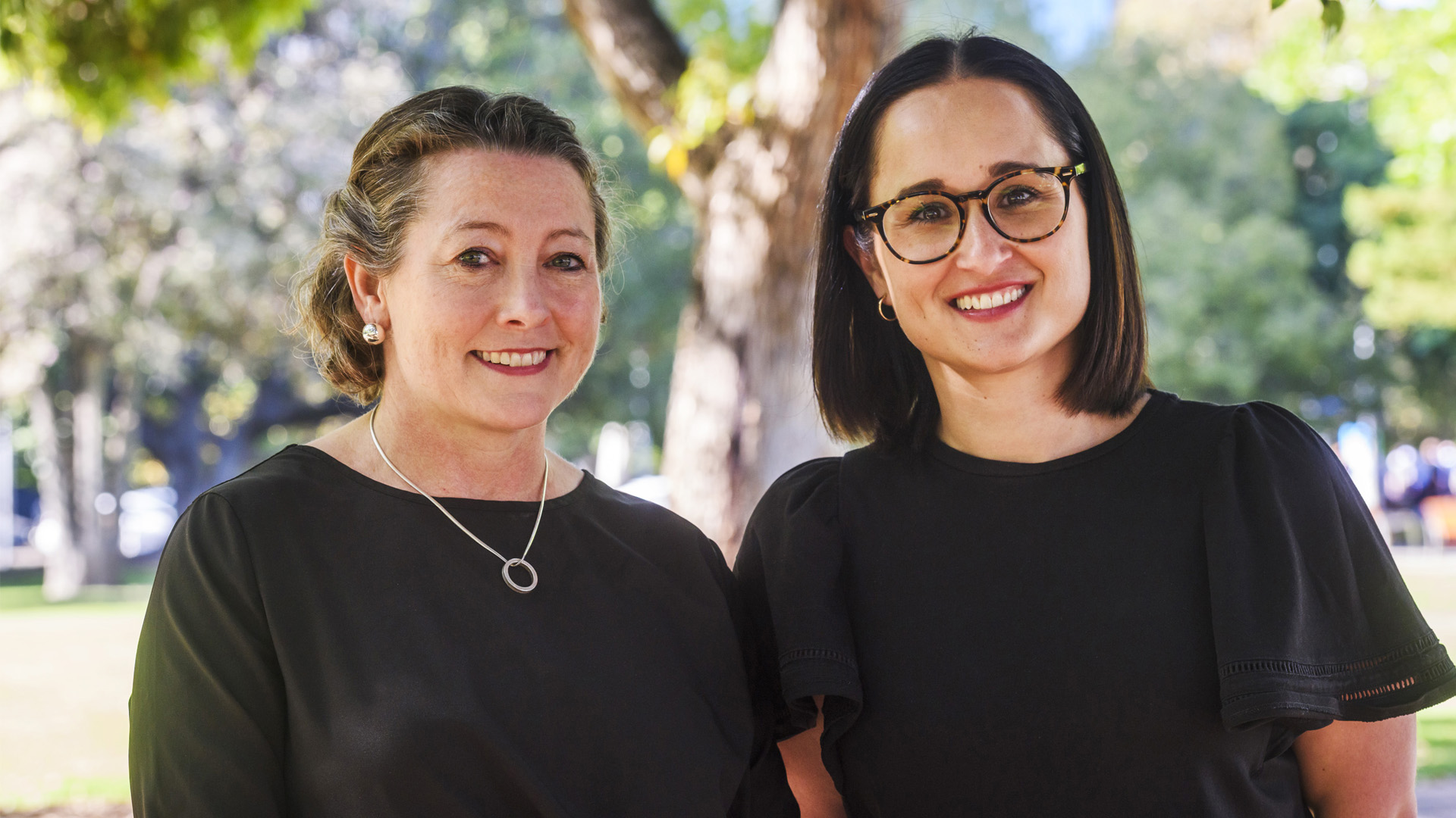 Two women standing outside in a park