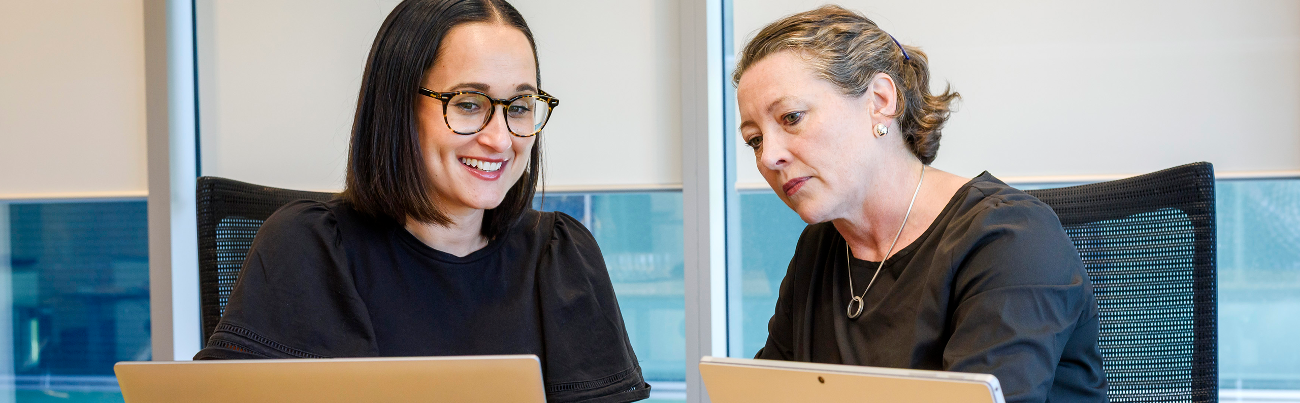Two women in a business setting looking at a computer screen