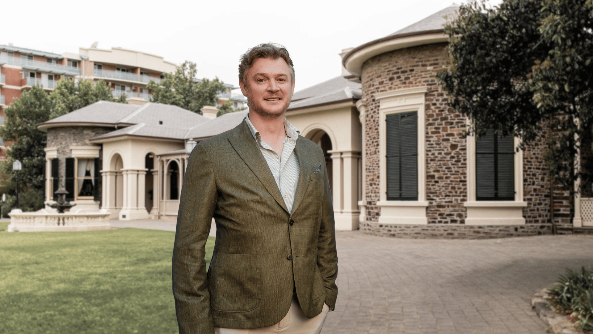A man in blazer standing in front of a house