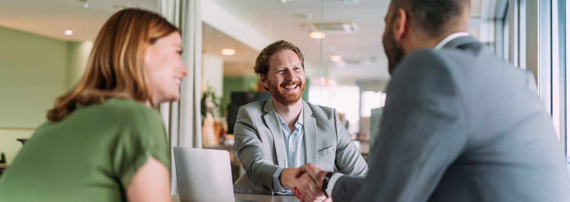 Business people handshaking across the table during a meeting in modern office.