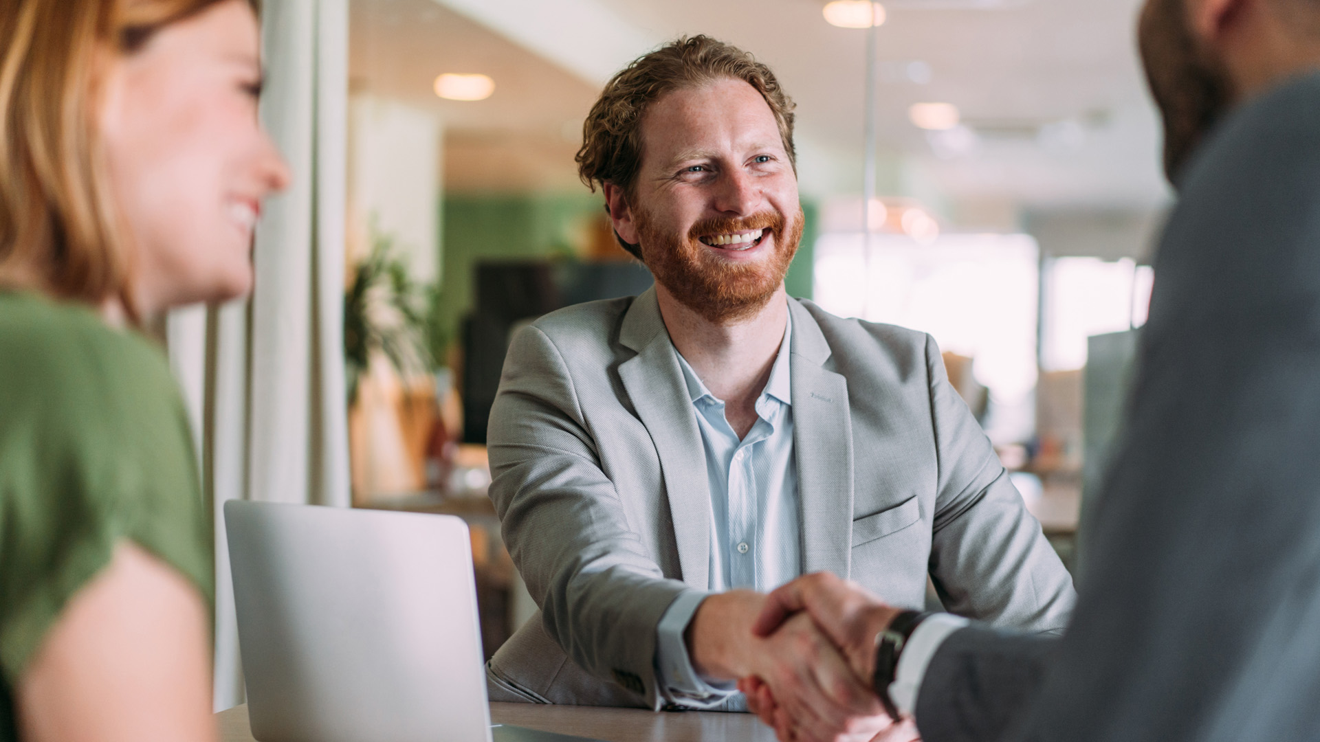 Business people handshaking across the table during a meeting in modern office.