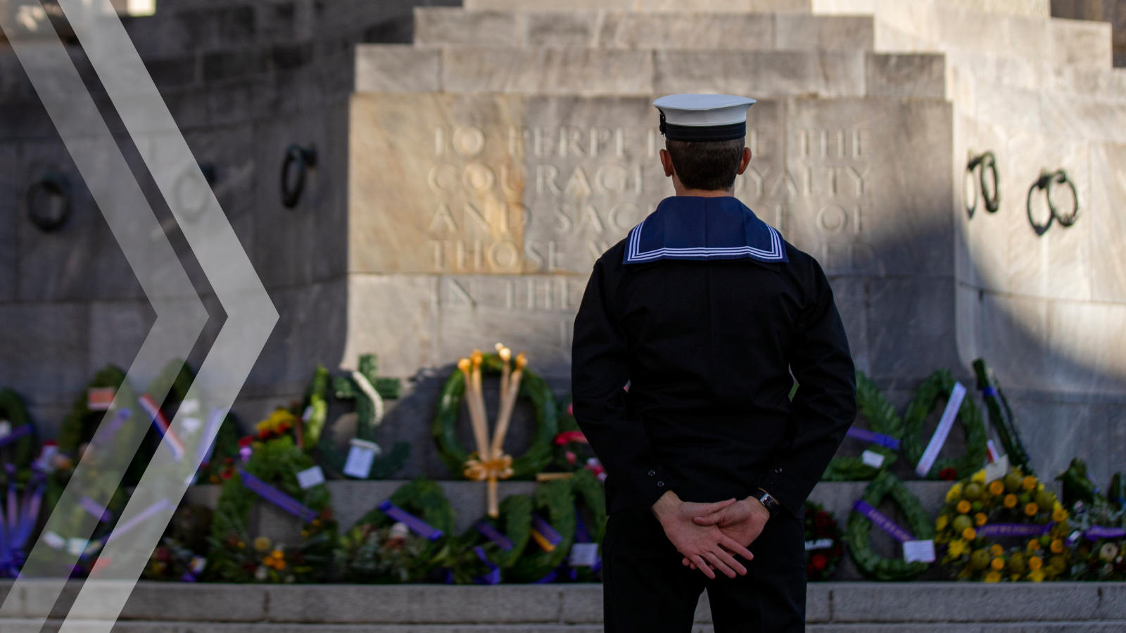 Australian Navy personnel standing before a war memorial during a commemorative service.