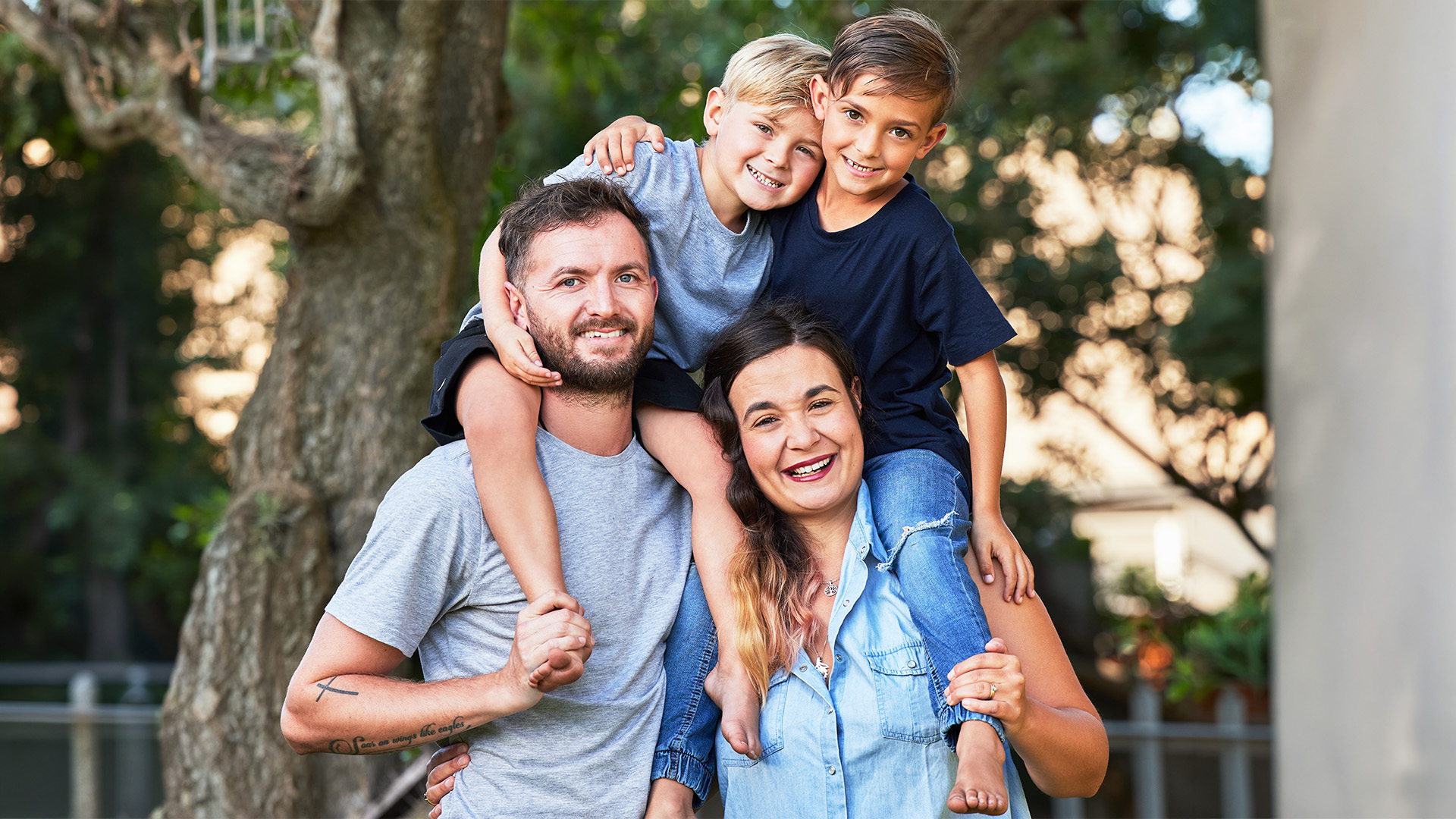 Portrait of a family with their sons on their shoulders in a park